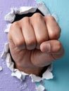 Fist breaking through colored wall symbolizing strength and defiance. Royalty Free Stock Photo