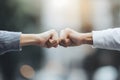 Fist bump gesture between two friends symbolizing teamwork, unity, and friendship in blurred outdoor Royalty Free Stock Photo