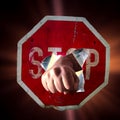 Fist of man punching through red traffic sign with inscription Stop, concept for overcoming, strength, assertiveness