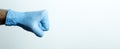 A fist in a medical glove. Doctor`s hand in a blue medical glove on a light background Royalty Free Stock Photo