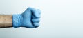 A fist in a medical glove. Doctor`s hand in a blue medical glove on a light background Royalty Free Stock Photo