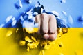 A fist punches through a concrete wall with the colors of the Ukrainian flag Royalty Free Stock Photo