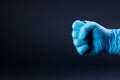 Fist of right man hand in a blue medical glove on a black background Royalty Free Stock Photo