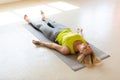 Fit adult woman lying on the mat in shavasana and practice yoga nidra the studio indoor, side front view, selective Royalty Free Stock Photo