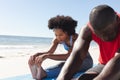 Fit african american couple practicing yoga, sitting and stretching on sunny beach Royalty Free Stock Photo