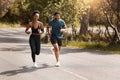 Fit african american couple running outdoors while exercising. Young athletic man and woman training to improve their Royalty Free Stock Photo