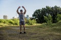 A fit asian guy does jumping jacks at a open field near the city. Cardiovascular fitness. Working out outdoors