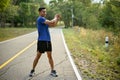 Fit Asian man stretching his arms and body, warming up before jogging or running in a park Royalty Free Stock Photo