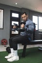 A fit asian man in a sweatshirt does seated dumbbell hammer curls. Working out and training biceps. Open air gym setting Royalty Free Stock Photo