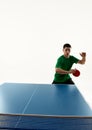 Fit Asian man, table tennis player in green sport uniform focused on ball for perfect hit against white background