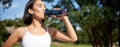 Fit asian sportswoman drinks water while running marathon. Fitness girl jogging in park, staying hydrated. Royalty Free Stock Photo