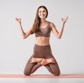 Fit asian woman in sportswear practicing yoga, keeping balance, while standing on a knees in difficult lotus pose.