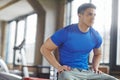 Fit athlete sitting alone in gym and taking break during his workout. Sporty, athletic, active, muscular man looking