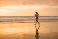 Fit and athletic Asian Chinese sporty woman running on beautiful beach doing jogging workout on sunset in fitness healthy lifestyl Royalty Free Stock Photo