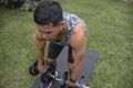 A fit and athletic asian man is working out outdoors at his lawn, doing dumbbell deadlifts. Fitness in middle age