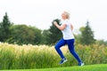 Fit athletic mature woman running alongside reeds Royalty Free Stock Photo