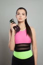 Fit beautiful female model brunette holding water bottle or proteine shake in her hand on gray background