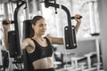 Fit beautiful young woman exercise workout on machine in gym. Glad smiling girl is enjoy with her training process.