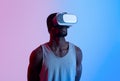 Fit black guy wearing VR headset, exercising with virtual reality gear in neon lighting