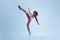 Fit black lady raising leg and showing perfect stretching, doing karate side kick over blue background, full length Royalty Free Stock Photo