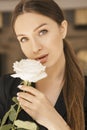 Fit brunette caucasian woman in dress and jacket at home. Pretty flawless face. She holds flower