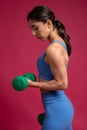 Fit brunette doing dumbbell bicep curl on maroon background Royalty Free Stock Photo