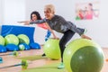 Fit Caucasian women doing crane exercise standing on one leg with their arms out to sides holding on to balance ball