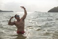 A fit and confident asian man does a classic aesthetic bodybuilding pose waist deep in the water Royalty Free Stock Photo