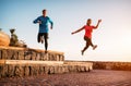 Fit couple doing workout running session at sunset outdoor - Sporty young people jogging next the beach