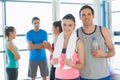 Fit couple with friends in background in exercise room