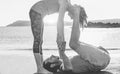 Fit couple preparing acro yoga position outdoor on the beach - People training in nature at sunset - Healthy lifestyle, meditation Royalty Free Stock Photo