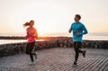 Fit couple running on sunset time next the beach - Sporty young people doing workout session outdoor Royalty Free Stock Photo