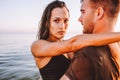 Fit couple in sea or ocean hug each other with love at summer sunset. Romantic mood, tenderness, relationship, vacation concept.