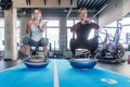 Fit couple working on bosu ball in fitness studio. Doing a squat exercise Royalty Free Stock Photo