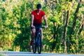 Fit cyclist rides his bicycle bike on an empty road in nature wearing a baseball hat and red t-shirt Royalty Free Stock Photo