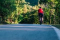 Fit cyclist rides his bicycle bike on an empty road in nature wearing a baseball hat and red t-shirt Royalty Free Stock Photo