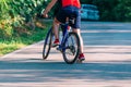 Fit cyclist rides his bicycle bike on an empty road in nature wearing a baseball hat and red t-shirt Royalty Free Stock Photo