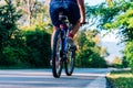 Fit cyclist rides his bicycle bike on an empty road in nature wearing a baseball hat and red t-shirt Royalty Free Stock Photo