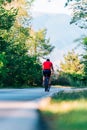 Fit cyclist rides his bicycle bike on an empty road in nature wearing a baseball hat and red t-shirt Royalty Free Stock Photo