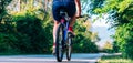 Fit cyclist rides his bicycle bike on an empty road in nature wearing a baseball hat and red t-shirt Royalty Free Stock Photo