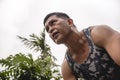 A fit and determined 50 year old asian man in a tank top and an intense ruthless look during a workout.