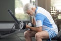 Fit elderly man working out with dumbbells in gym.