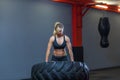 Fit female athlete working out with a huge tire, turning and carry in the gym. Crossfit woman exercising with big tire Royalty Free Stock Photo