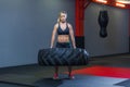 Fit female athlete working out with a huge tire, turning and carry in the gym. Crossfit woman exercising with big tire Royalty Free Stock Photo