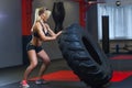 Fit female athlete working out with a huge tire, turning and carry in the gym. Crossfit woman exercising with big tire Royalty Free Stock Photo