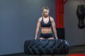Fit female athlete working out with a huge tire, turning and carry in the gym. Crossfit woman exercising with big tire Royalty Free Stock Photo