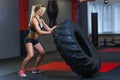 Fit female athlete working out with a huge tire, turning and carry in the gym. Crossfit woman exercising with big tire Royalty Free Stock Photo