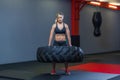 Fit female athlete working out with a huge tire, turning and carry in the gym. Crossfit woman exercising with big tire Royalty Free Stock Photo