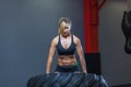 Fit female athlete working out with a huge tire, turning and carry in the gym. Crossfit woman exercising with big tire Royalty Free Stock Photo