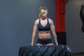 Fit female athlete working out with a huge tire, turning and carry in the gym. Crossfit woman exercising with big tire Royalty Free Stock Photo